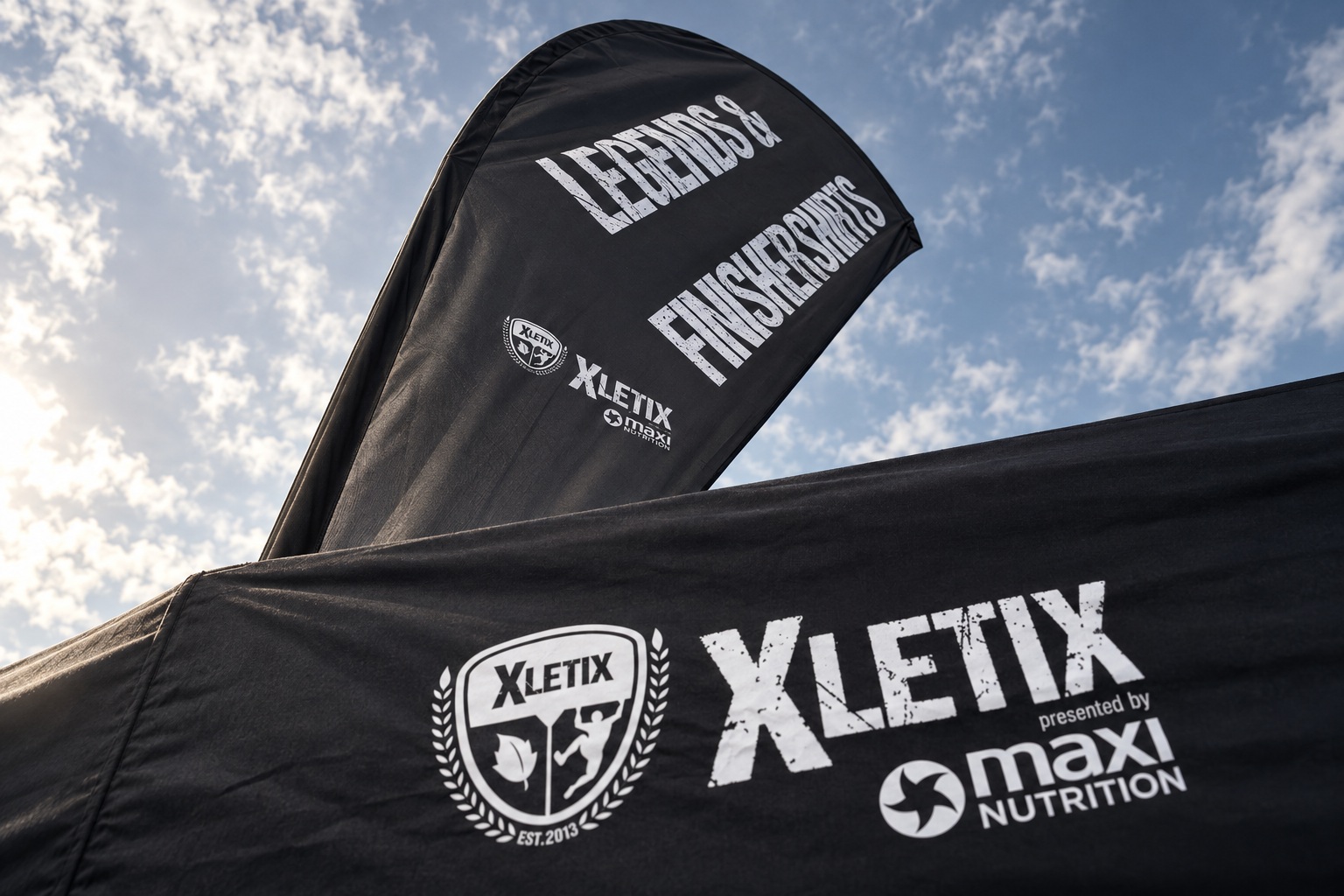 Schwarze Fahne mit LEGENDS und FINISHER-SHIRTS über einem Zeltdach