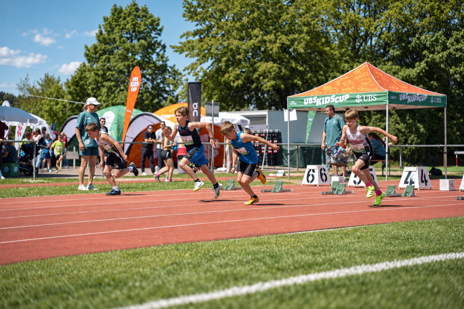Kinder beim Sprint mit orange-grünem UBS-Kids-Cup-Zelt im Hintergrund